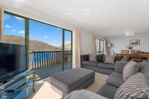 Il comprend un salon avec un canapé, une télévision et un balcon. dans l'établissement Marina Heights, à Queenstown