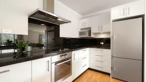 une cuisine avec des armoires blanches et un réfrigérateur en acier inoxydable dans l'établissement Marina Heights, à Queenstown