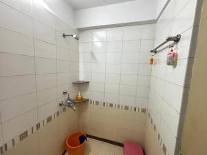 une salle de bain avec douche aux murs carrelés blancs dans l'établissement SATVIK STAy, à Navi Mumbai