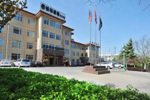a building with an american flag in a parking lot at GreenTree Inn Shandong Yantai Penglai Pavilion Bus station Express Hotel in Penglai