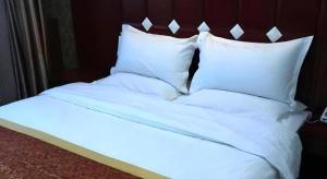 a bed with white sheets and pillows at Shell Hotel Taiyuan South Railway Station New Southeast Bus Station in Taiyuan