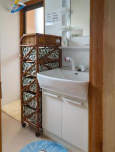 La salle de bains est pourvue d'un lavabo et d'une étagère avec des bouteilles de vin. dans l'établissement ゲストハウス634庵, à Sango