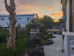un jardin avec une fontaine en pierre et un arbre dans l'établissement ゲストハウス634庵, à Sango