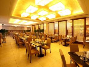 a restaurant with tables and chairs and a large ceiling at Qingdao Blue Horizon Hotel Licang in Laoshan