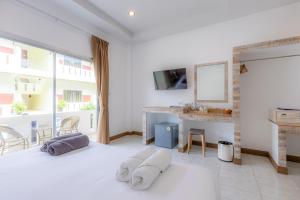 a white living room with a table and a mirror at Sunrise Serenity Phuket Resort in Karon Beach