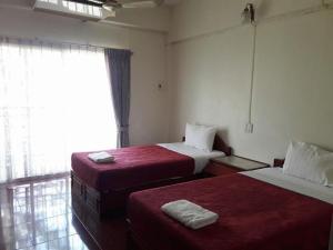 a room with two beds with red sheets and a window at Rawanda Resort Hotel in Ban Khlong Pho
