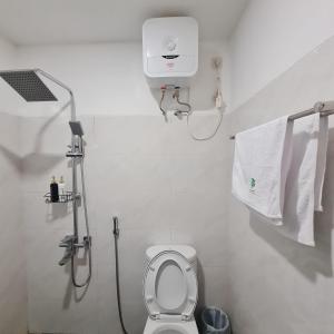 a bathroom with a toilet and a shower and towels at Menoreh Farm Stay Samigaluh Kulonprogo in Kalirejo