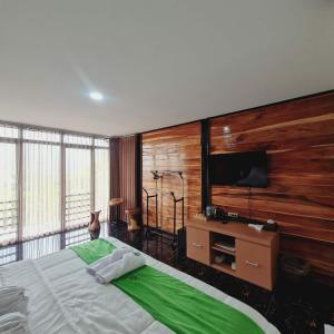 a bedroom with a large bed and a flat screen tv at Menoreh Farm Stay Samigaluh Kulonprogo in Kalirejo