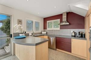 a large kitchen with a counter top and red walls at Vancouver Spa Views in Queenstown +22 photos