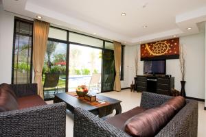 a living room with two couches and a television at Palm Grove Resort, Pattaya in Na Jomtien