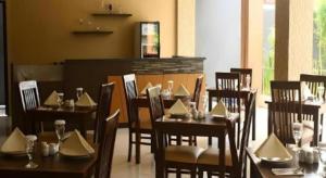 Un restaurante con mesas y sillas de madera con servilletas. en Mataram Square Hotel, en Tanjungkarang