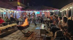 Ein Mann steht vor einem Kaminfeuer in einem Raum mit einer Menschenmenge in der Unterkunft Balthali Village Resort-Balthali in Panaoti