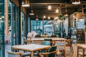 ein Restaurant mit Tischen und Stühlen und Fenstern in der Unterkunft Eco Cozy Beachfront Resort Chaam in Ban Tha Sai