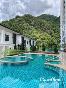 a swimming pool in front of a building with a mountain at Onsen Suite Theme Park View in Ipoh
