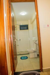 a bathroom with a toilet and a glass door at Carlton Stays in Nanyuki