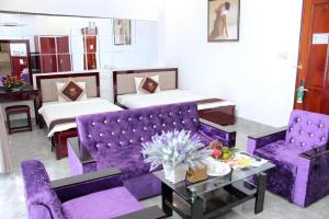 ein Wohnzimmer mit lilafarbenen Möbeln und 2 Betten in der Unterkunft Tran Vinh Hotel in Bạc Liêu
