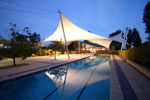 a large swimming pool with a canopy on top of it at Chateau Elan At The Vintage in Pokolbin