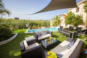 un patio con sillas y mesas y una piscina en Gold Sand Villa, en Protaras