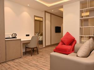 a living room with a couch and a red chair at Arth Boutique and Hotel in Kota