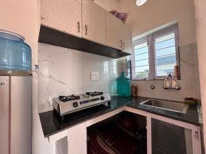 a kitchen with a stove top oven next to a sink at Panwar peaceful homestay in Jhājra