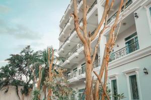Un gran edificio blanco con árboles delante. en Boutique Kampot Hotel, en Kampot