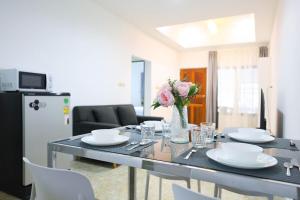 Sisters Ari 2-bedrooms house, Bang Tao beach في Ban Thalat Choeng Thale: طاولة طعام مع صحون و إناء من الزهور