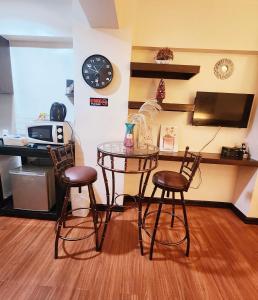 einem Tisch mit zwei Stühlen und einer Uhr an der Wand in der Unterkunft Tagaytay Condo Staycation- Taal-view with balcony in Iruhin