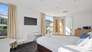 a bedroom with a large bed and a tv at Marina Apartment 406 in Queenstown