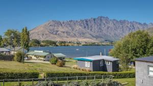 a house with a lake and mountains in the background at Marina Apartment 406 in Queenstown