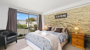 a bedroom with a bed and a chair and a window at Couple’s Retreat in Queenstown