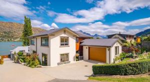 a house with a garage in front of a lake at Couple’s Retreat in Queenstown +6 photos