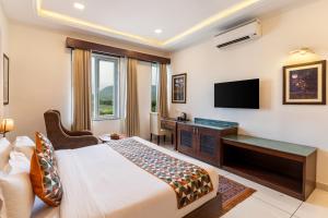 a hotel room with a bed and a desk and a television at The Colonial - A Lake View Hotel in Udaipur in Udaipur