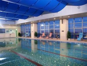 ein großer Pool mit Wasser in einem Gebäude in der Unterkunft Ramada Plaza by Wyndham Hangzhou Riverside in Hangzhou