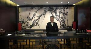 Ein Mann steht vor einem großen Bildschirm. in der Unterkunft Hangzhou Qiao Garden Vacation Hotel in Hangzhou