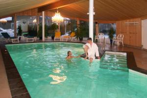 a man and a woman sitting in a swimming pool at Alpen Chalet in Kandersteg