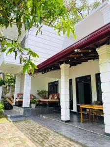 a porch of a house with a picnic table at Kuchu surf hostel in Weligama