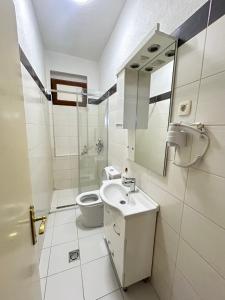 a white bathroom with a toilet and a sink at Apartment Centar in Podgorica +17 photos