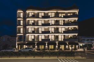 ein hohes weißes Gebäude mit davor geparkt in der Unterkunft Luminoso Boutique Hotel in Budva