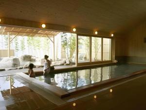 uma mulher e uma criança sentados numa piscina em Hirata Maple Hotel em Kozakai