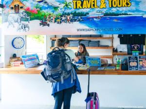 een vrouw met een rugzak aan een balie bij Bad Monkey Samui Hostel in Chaweng Beach