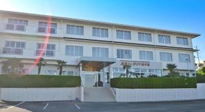 Un gran edificio blanco con palmeras en un estacionamiento. en Anori Seaside Hotel, en Ōsasu