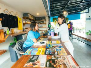 twee vrouwen zitten aan een tafel met tijdschriften erop bij Bad Monkey Samui Hostel in Chaweng Beach