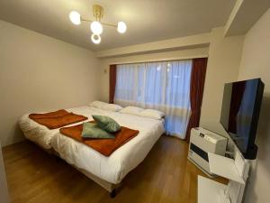a bedroom with a bed and a flat screen tv at カピテーヌ琴似 in Sapporo