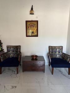 zwei Stühle und ein Tisch mit einem Bild an der Wand in der Unterkunft The Coffee Retreat in Mudigere