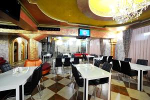 un restaurante con mesas blancas y sillas negras en Rich Hotel, en Bishkek