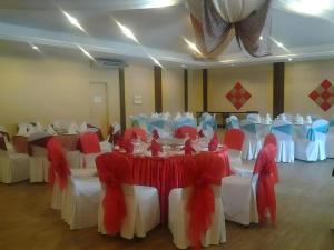 a banquet hall with white and red tables and chairs at Disini Hotel in Kampong Sembulan