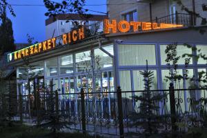 a hotel with a sign on top of a building at Rich Hotel in Bishkek