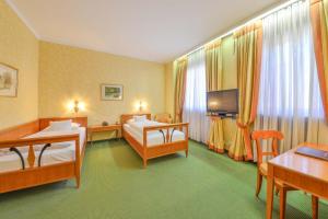 a hotel room with two beds and a television at Romantik Hotel zur Post in Fürstenfeldbruck