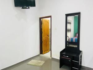 a mirror and a dresser with a door in a room at J City Holidays Inn in Jaffna