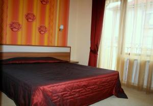 a bedroom with a red bed and a window at Hotel Elegant in Karnobat